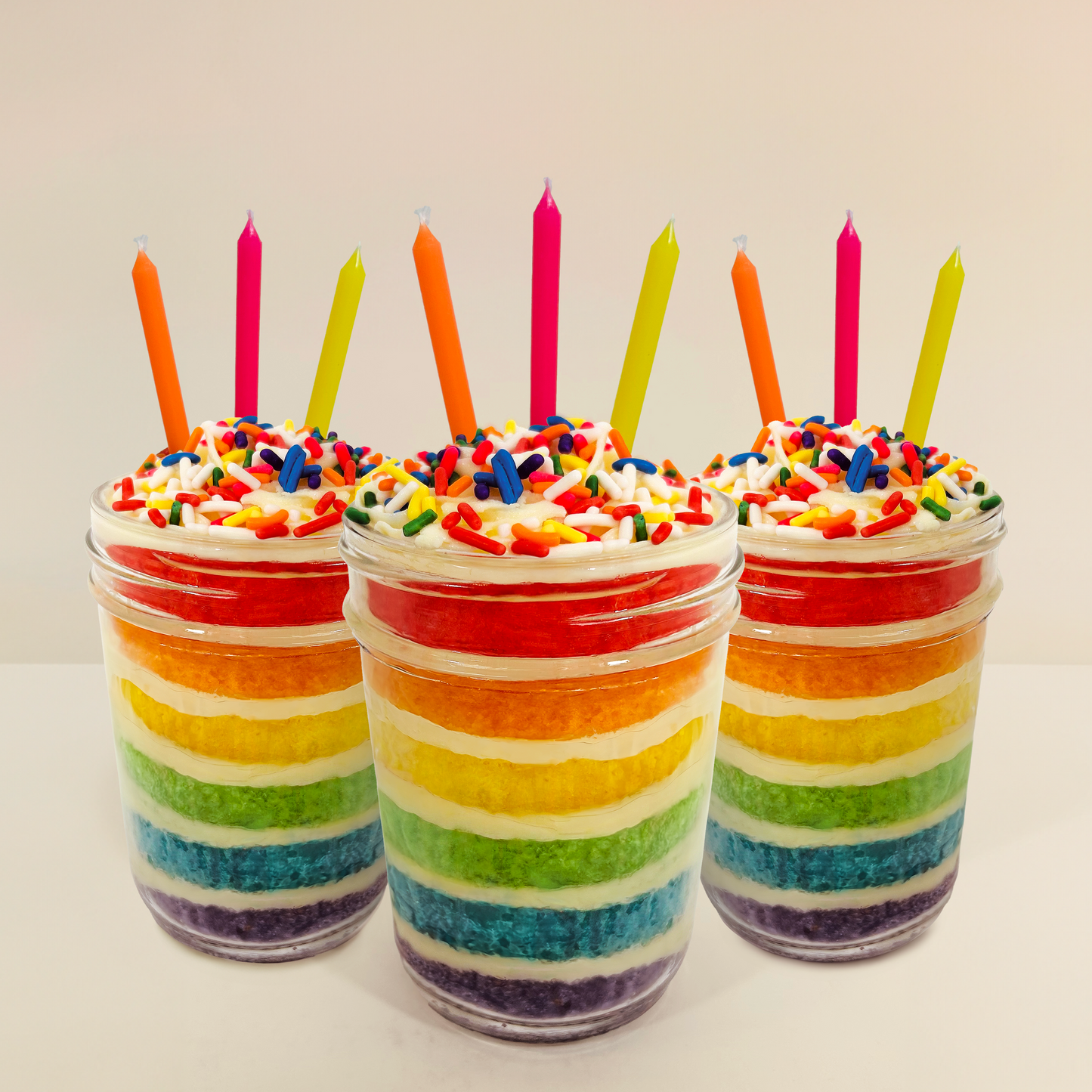 Close-up of rainbow layered vanilla cake inside a rainbow kosher cupcake jar.