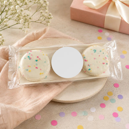 Three white chocolate dipped Oreos in a cellophane sleeve with a blank white round sticker, ready for a custom logo