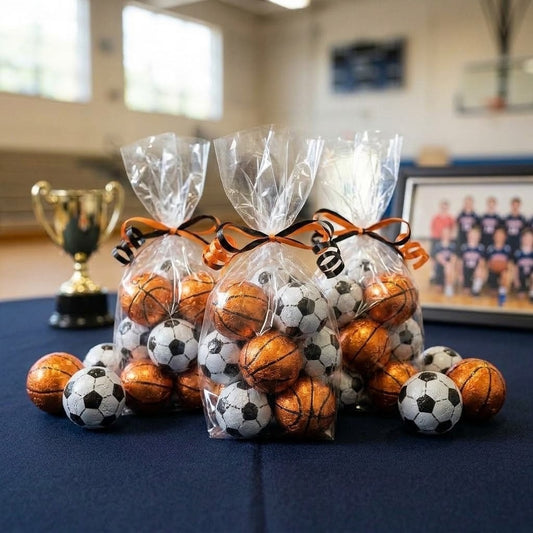 Chocolate basketballs and soccer balls packed in clear cellophane party favor bags tied with orange and black ribbon