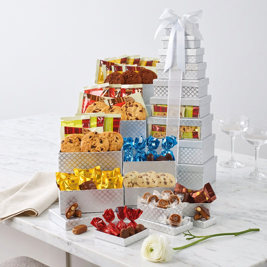 Capture Their Attention snack gift tower with silver gift boxes of cookies, chocolates and caramels stacked and tied with a white bow