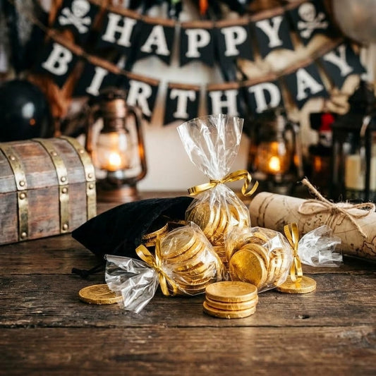 Gold foil-wrapped chocolate coins packed in clear cellophane party favor bags tied with gold ribbon at a pirate party