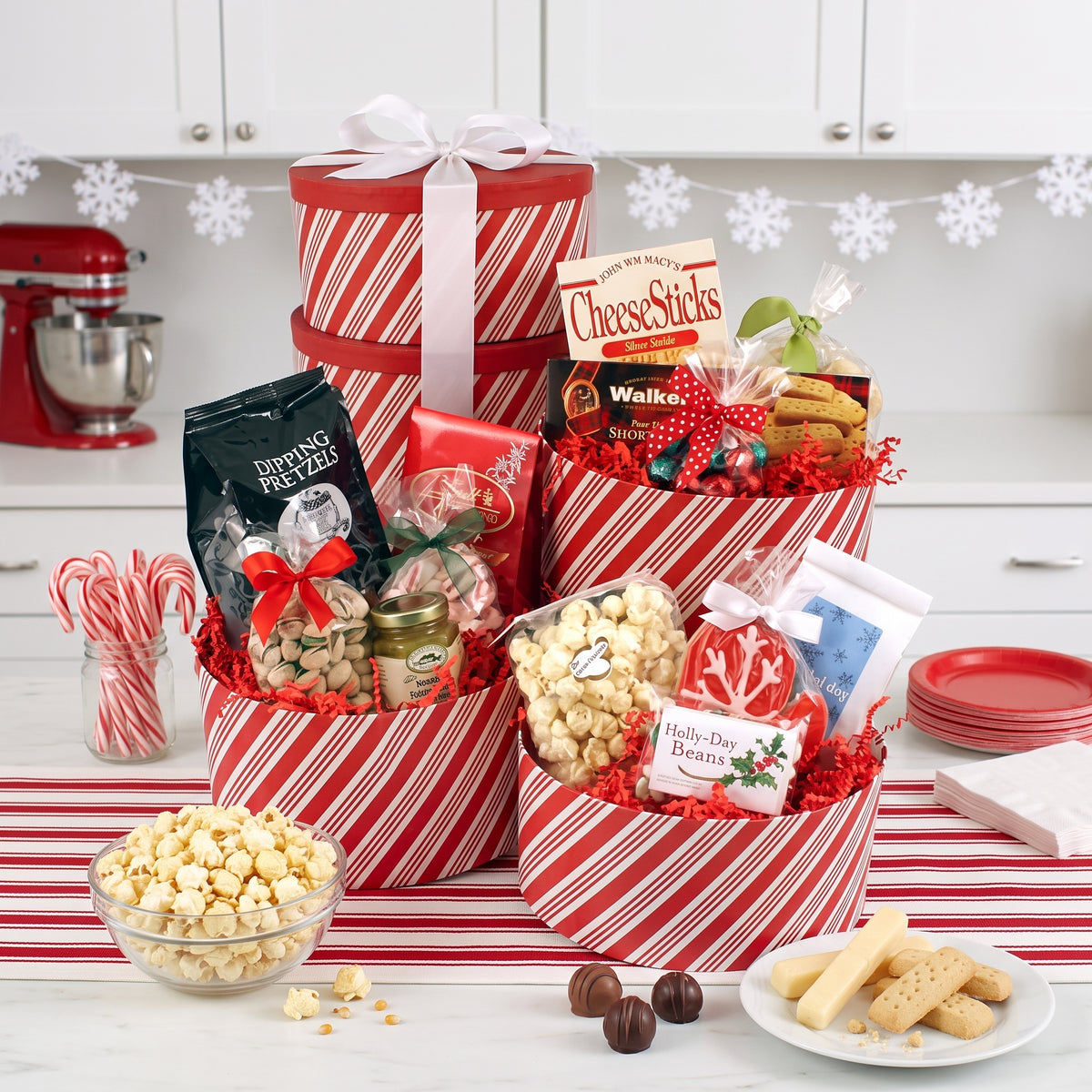 Holiday bonanza Christmas gift boxes stacked in peppermint stripe with cookies, pretzels, popcorn and chocolates, on a kitchen island at a holiday party
