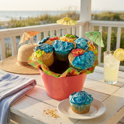 Beach Cupcake Bouquet of seven cupcakes with blue buttercream waves, graham cracker sand and paper umbrellas in a coral pail on a seaside porch, kosher, made in Chestnut Hill MA