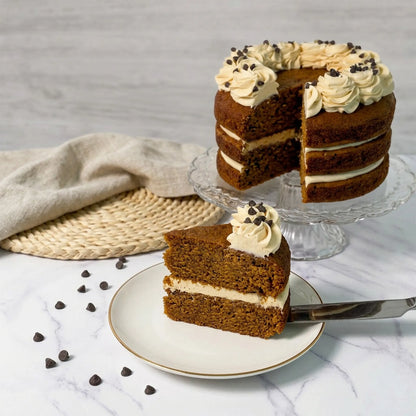 Sliced chocolate chip pumpkin cake showing three spiced layers and cinnamon buttercream filling, with a slice on a plate, kosher, made in Chestnut Hill MA