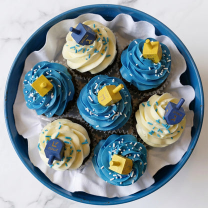Overhead view of the Dreidel Cupcake Bouquet with blue and ivory buttercream swirls, sprinkles and wooden dreidels, kosher, made in Chestnut Hill MA