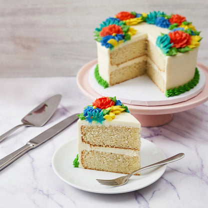 Slice of floral cake showing vanilla layers and buttercream filling, with the cut green floral cake behind it, kosher, made in Chestnut Hill MA