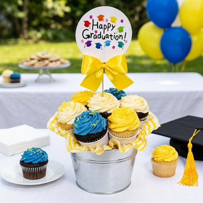 Happy Graduation Cupcake Bouquet of blue, yellow and white buttercream cupcakes with a Happy Graduation topper and yellow bow in a galvanized bucket at an outdoor party, kosher, made in Chestnut Hill MA