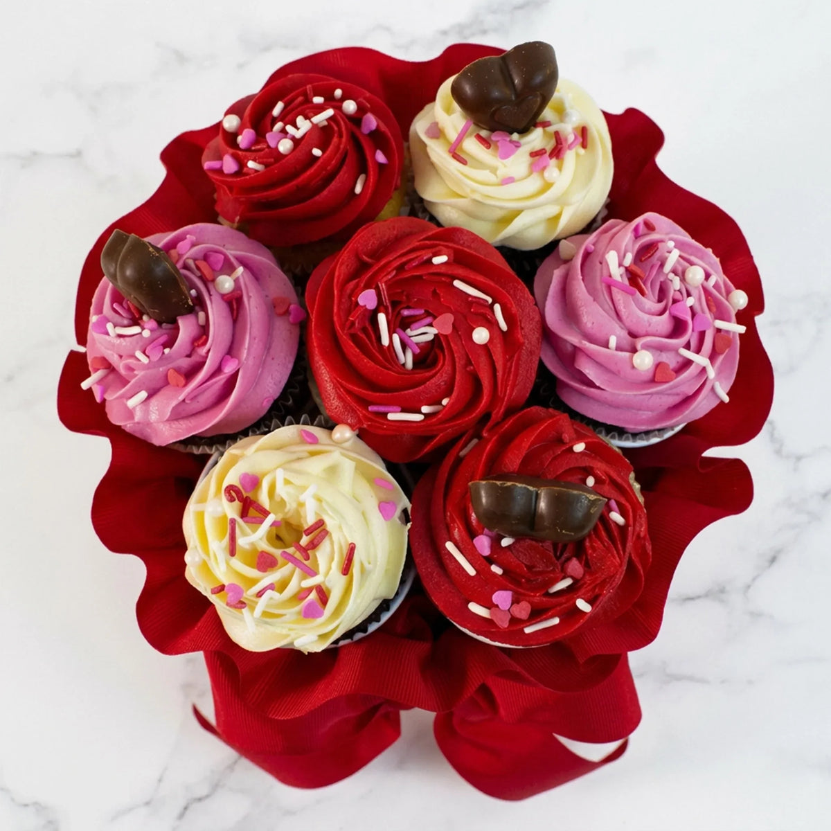 Top view of a Valentine cupcake bouquet with red, pink and cream buttercream swirls, heart sprinkles and chocolate hearts, kosher, made in Chestnut Hill MA
