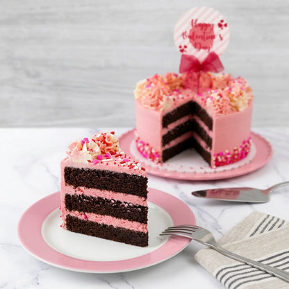 Slice of Valentine's Day sprinkles cake showing chocolate layers with pink buttercream, with the cut cake behind it, kosher, made in Chestnut Hill MA
